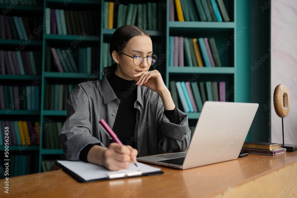 A woman with glasses is a designer who works, uses a laptop computer, communicates online with a client. A woman with glasses is a designer who works, uses a laptop computer, communicates online with a client.