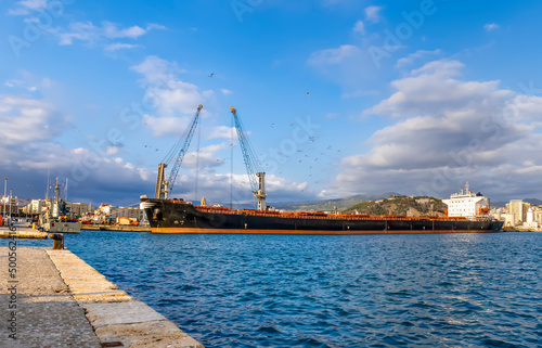 View of the port with a long industrial boat and cranes