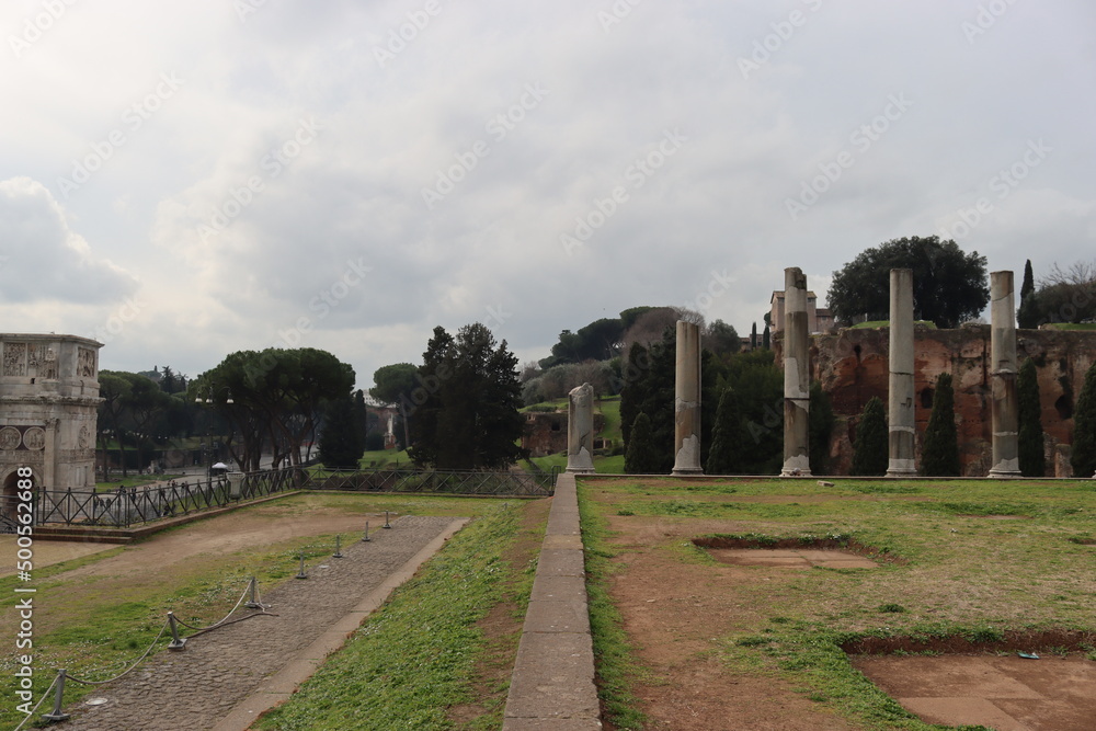 ROME, ITALY - February 05, 2022: Panoramic view around the Colosseum in city of Rome, Italy. Cold and gray sky in the background. Macro photography of the green parks with the old buildings.