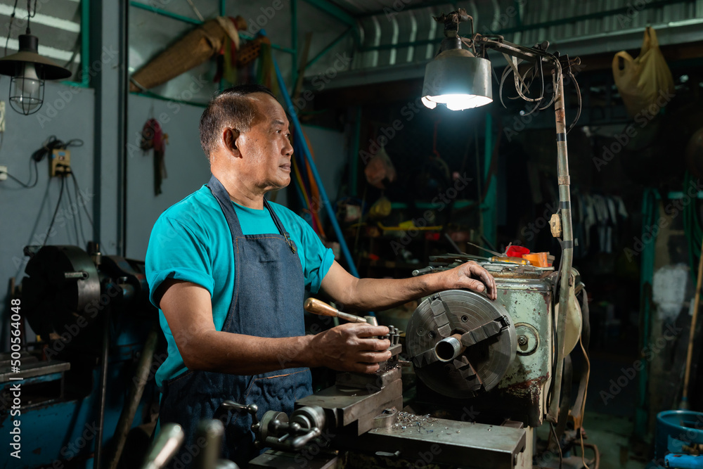 Portrait of Asian senior man working as a steel lathe is preparing work and equipment to turn steel and a small lathe in the family industry. Portrait of Asian senior man working as a steel lathe is preparing work and equipment to turn steel and a small lathe in the family industry.