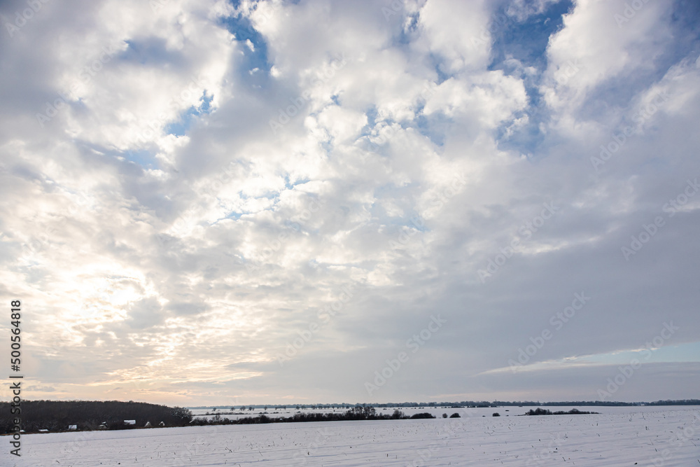 Obraz premium Natural sunset sunrise over field or meadow. The color of the sky over the winter snowy ground. Landscape under a picturesque sky at sunset. Dawn of the sun.