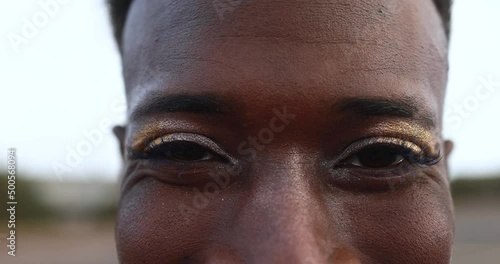 Happy gay african man with make-up smiling on camera outdoor photo