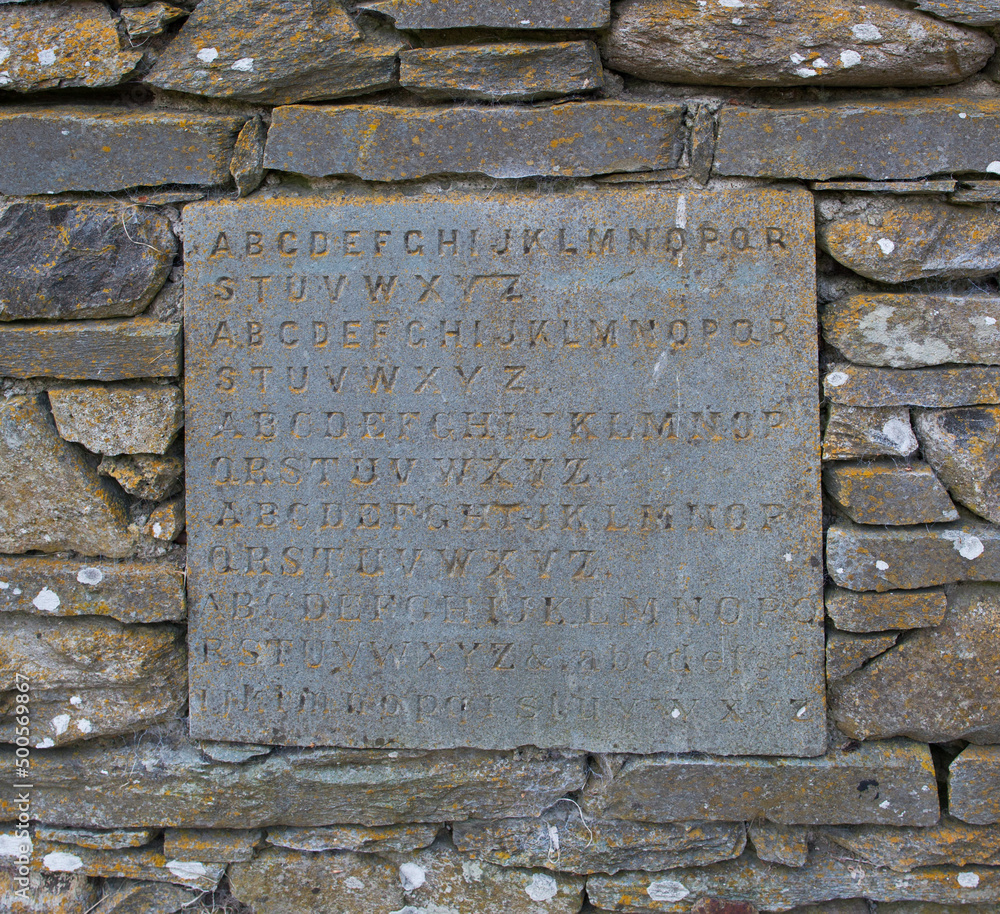 An ancient stone-mason apprentice piece with upper and lowercase lettering built into a wall.
