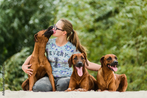 Smiling girl hugging and kissing her three happy dogs
