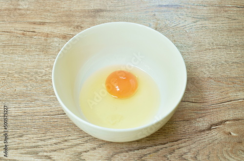 raw egg with yolk  in bowl on table