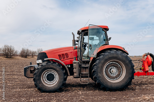 Spring sowing season. Farmer with a tractor sows corn seeds on his field. Planting corn with trailed planter. Farming seeding. The concept of agriculture and agricultural machinery.