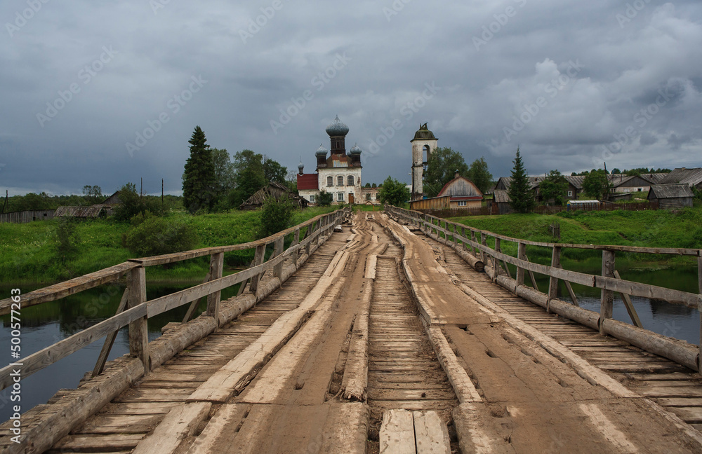 The bridge over the Ken River and Pyatnitskaya Church. Arkhangelsk region. Russia The bridge over the Ken River and Pyatnitskaya Church. Arkhangelsk region. Russia