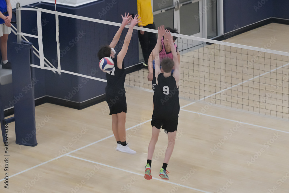 Male volleyball player hits the ball through the block