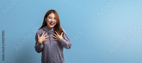 Portrait of beautiful Asian woman gesturing surprise on isolated background, portrait concept used for advertisement and signage, isolated over blue background, copy space.