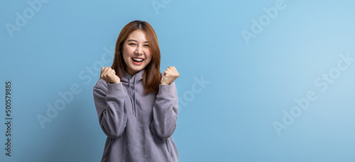Portrait of beautiful Asian woman doing cheerful pose on isolated background, portrait concept used for advertisement and signage, isolated over blue background, copy space.