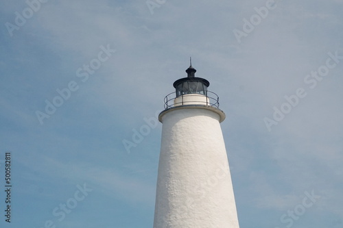 Top of White Lighthouse Against Very Blue Skky with Wisps of White Clouds on Sunny Day