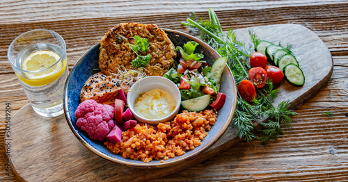 Vegan plate with millet cutlet, bulgur groats and vegetables