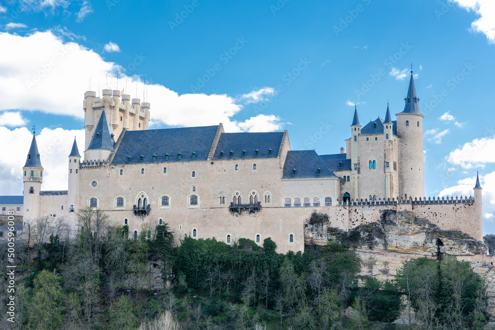 views of the alcazar of Segovia with tourists walking under its arches in Segovia
