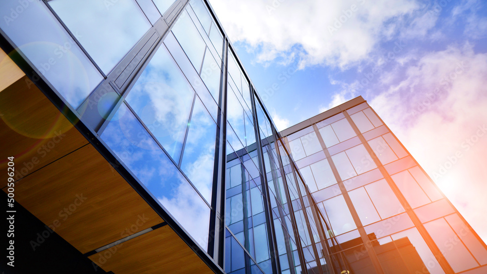 Obraz premium Glass buildings with cloudy blue sky background. Perspective wide angle view to steel light blue background of glass. Commercial modern city of future. Business concept of successful architecture.