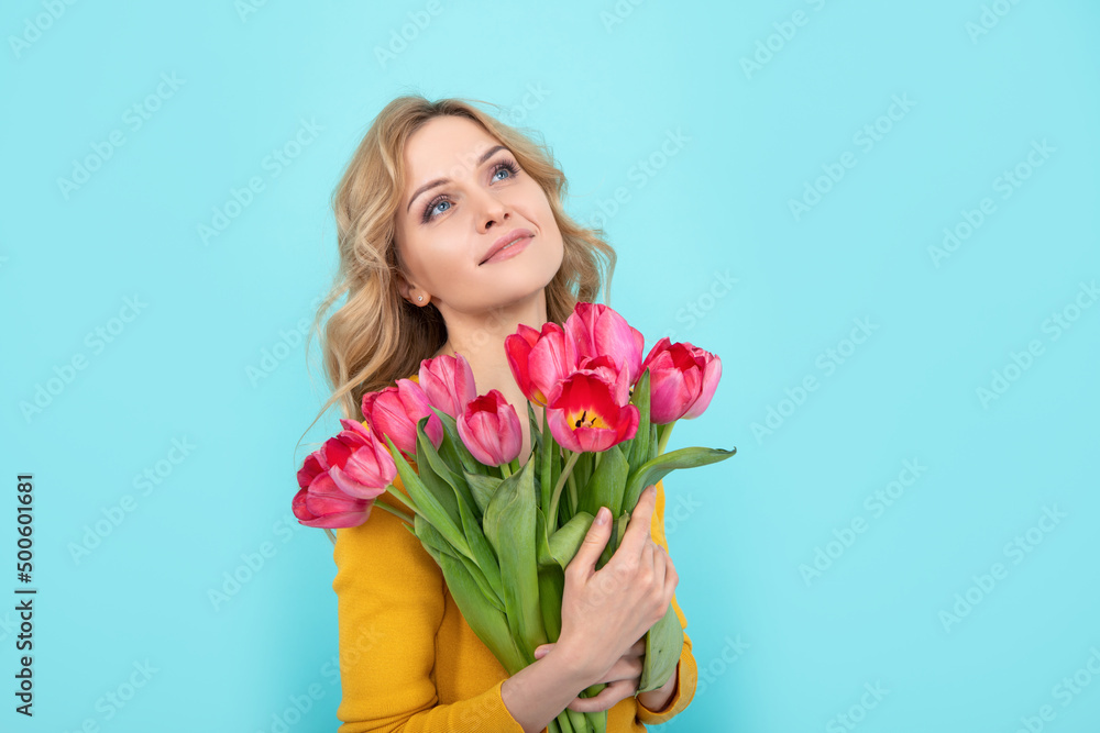 dreamy happy young woman with spring tulip flowers on blue background