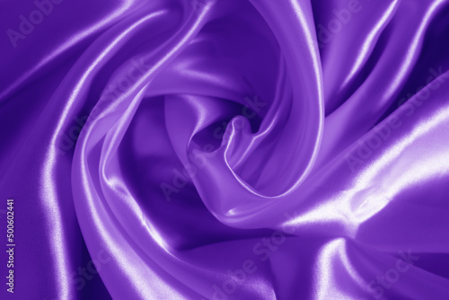 The texture of the proton purple cloth with waves and shrugs. Shiny fabric.