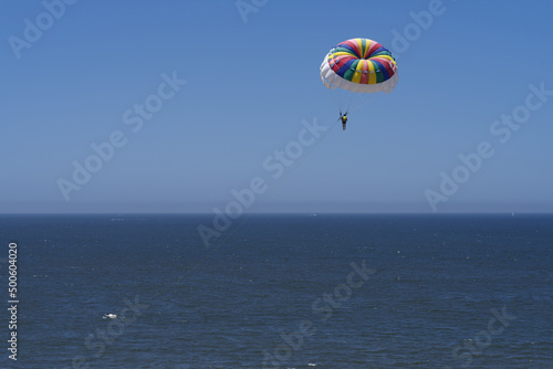 Image of a parasailer in mid air, blue sky and sea, shown in Puerto Vallarta, Mexico.