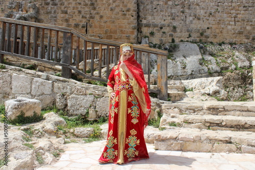 A woman in the national costume of the Bedouin nomads in Jordan during the Crusaders times against the backdrop of the fortress walls of the Ajlun castle.