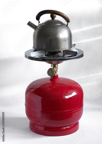 Kettle on the compact metal gas cylinder and burner for camping stove. photo