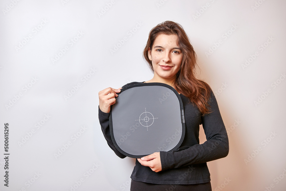 Pretty girl with a smile holds a gray card to register the correct colors on the camera. Pretty girl with a smile holds a gray card to register the correct colors on the camera.