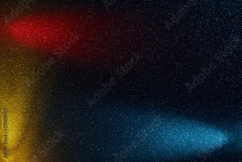 On a dark blue background in fine grain  rays of red yellow and light blue light