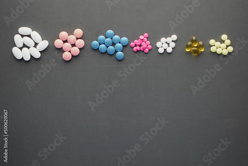  top view of any colorful pills and capsules on black background 