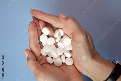 White pills in the palms. Handful of medicines in hand. Treatment, health care, medicine, vitamins, drugs.