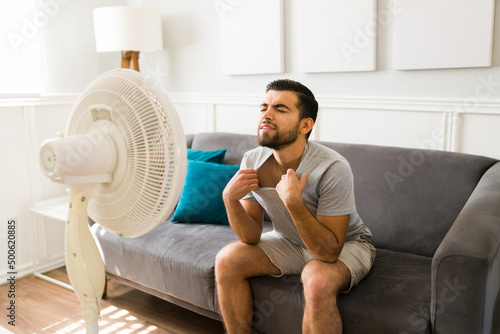 Foto Tired man cooling in front of the electric fan