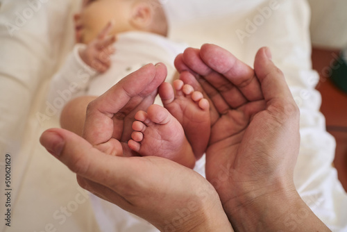 small legs of a newborn baby in female palms. love, motherhood, care