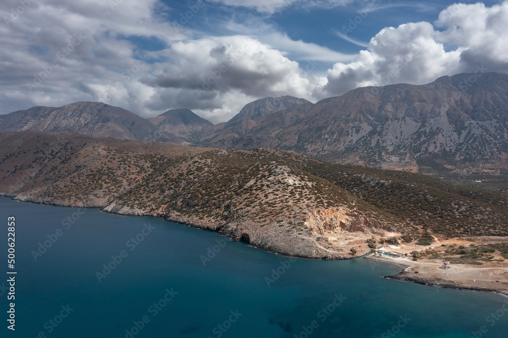 Mediterranean coastline with mountains rocks and transparent sea water under cloudy sky Crete Greece