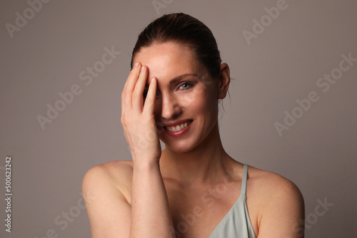 Smiling and optimistic woman with glowing skin and natural makeup at studio. 