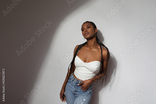 Portrait of African young woman with long braids posing on grey background.