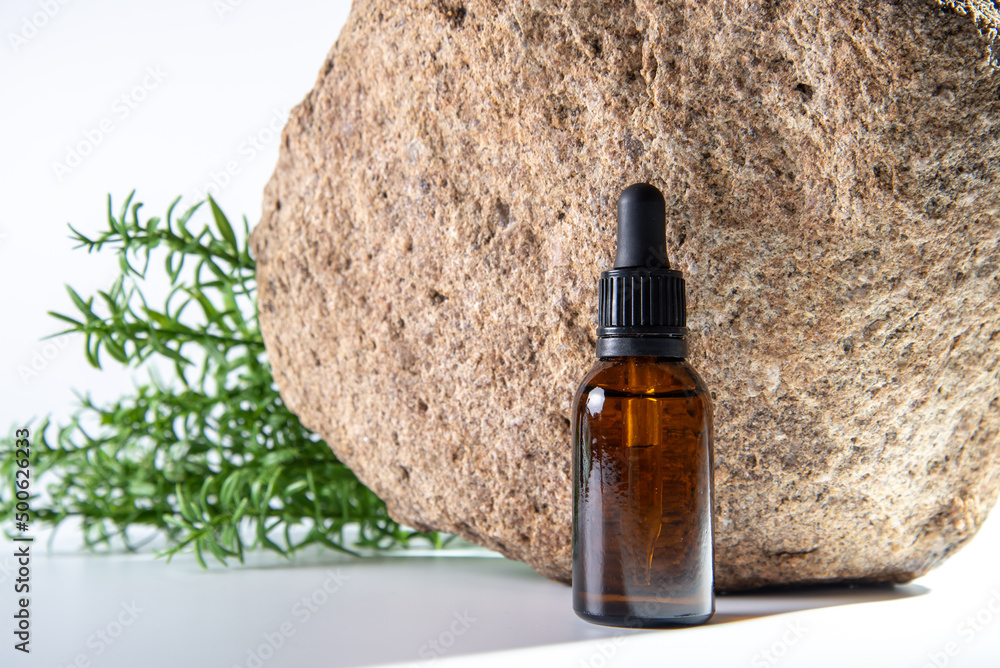 Cosmetic oil in a brown bottle with a pipette on a stone background. Cosmetic oil in a brown bottle with a pipette on a stone background.