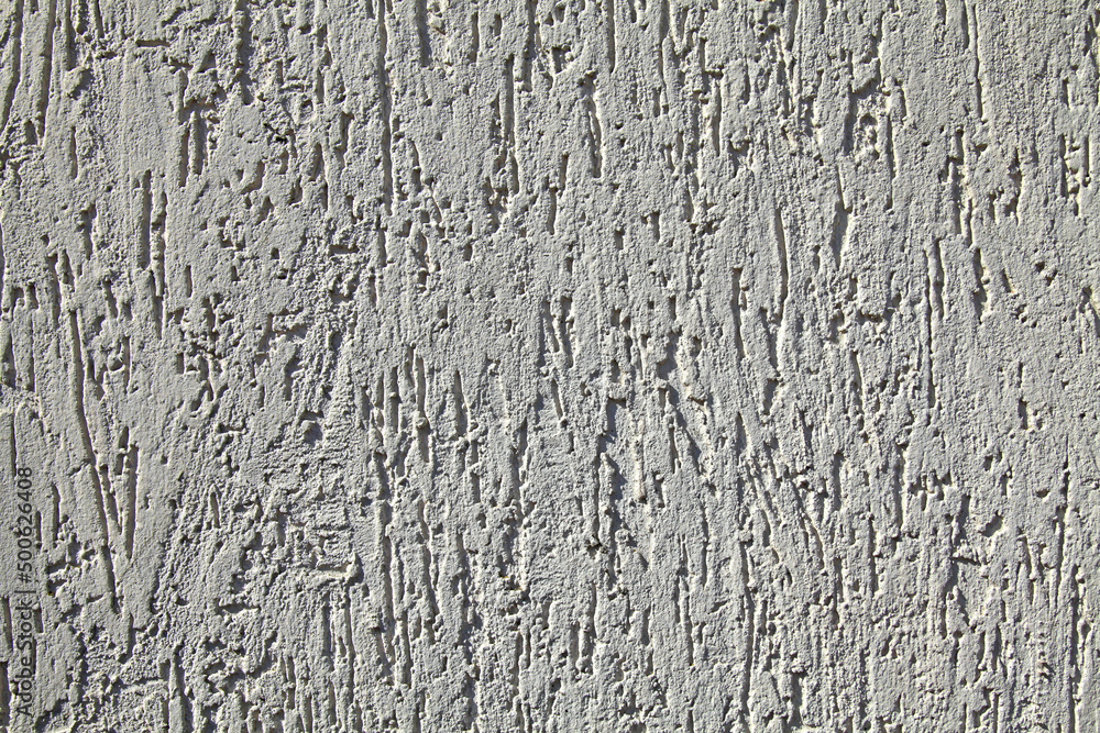 Grey wall, texture, background. Plastered building wall. Decorated surface with vertical embossed pattern. Chaotic, abstract strokes on the wall surface. Elements of the exterior and interior