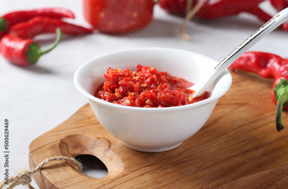 Sauce adjika with hot chili pepper or paste harissa in bowl on wooden board Sauce adjika with hot chili pepper or paste harissa in bowl on wooden board