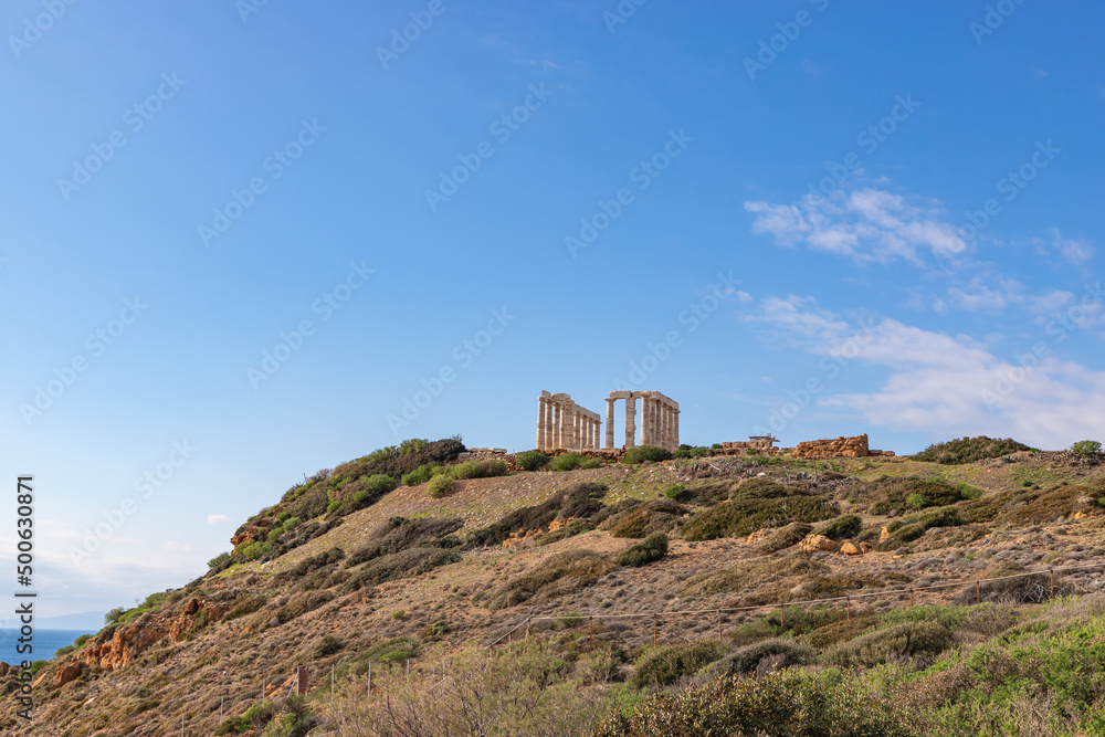 The Temple of Poseidon on a rock rises above the blue sea. Europe, Greece, Cape Sounion, Aegean Sea