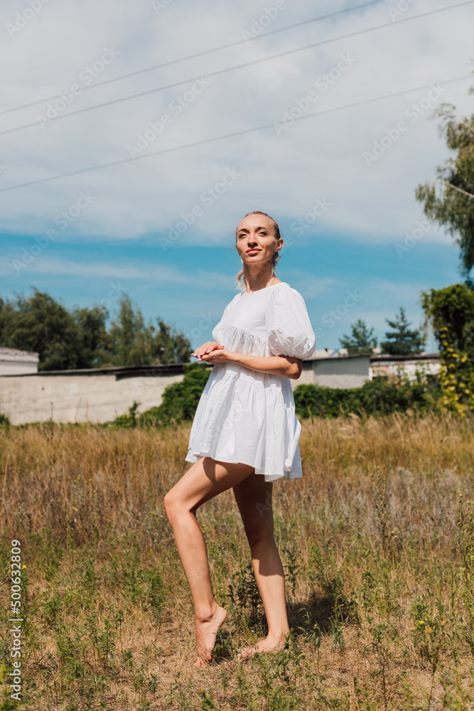 A young woman stands in a field and looking into the distance