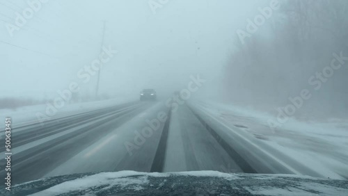 Blizzard on the highway. POV driving in a snowstorm with traffic. Whiteout conditions in Ontario, Canada.