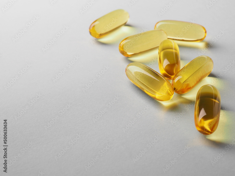 Fish oil. Yellow softgels lie on a white or light gray surface