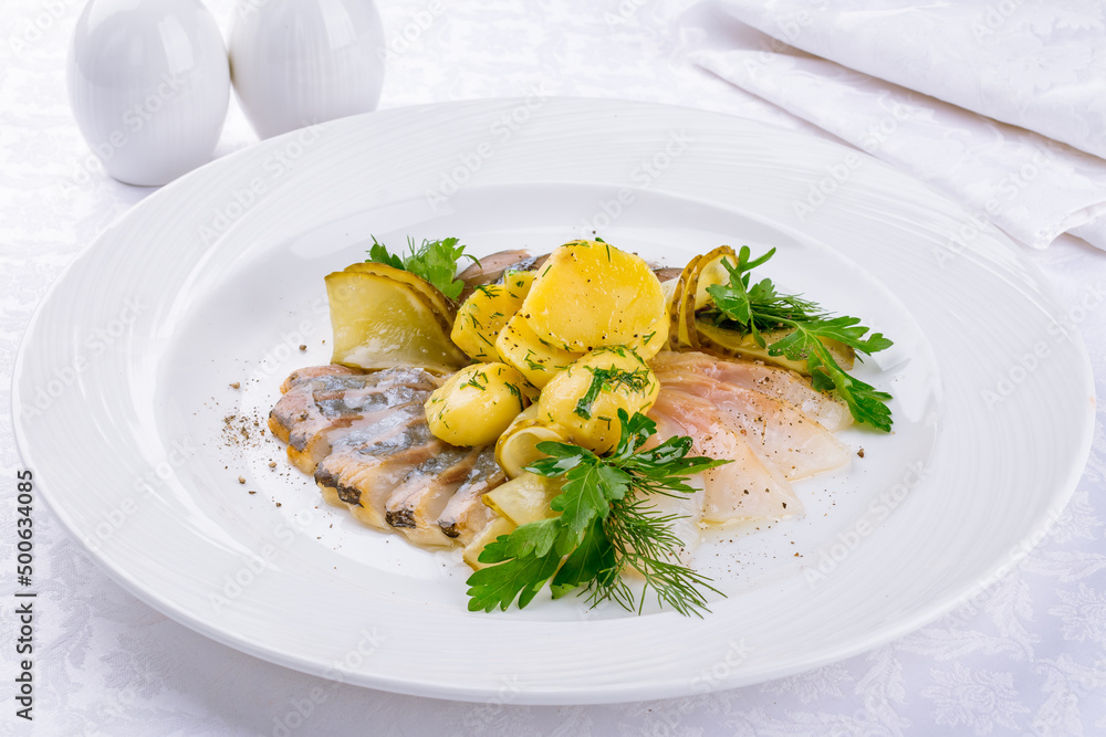 Herring with potatoes and onion on a white plate