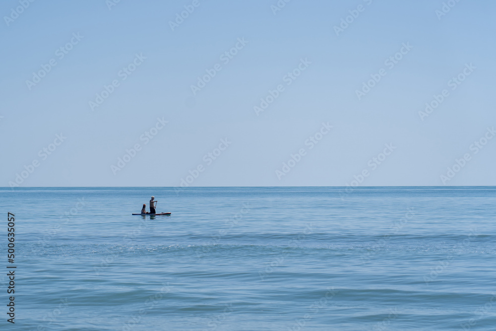 Fototapeta premium personas encima de una tabla de surf remando por la playa en el mar de oropesa españa