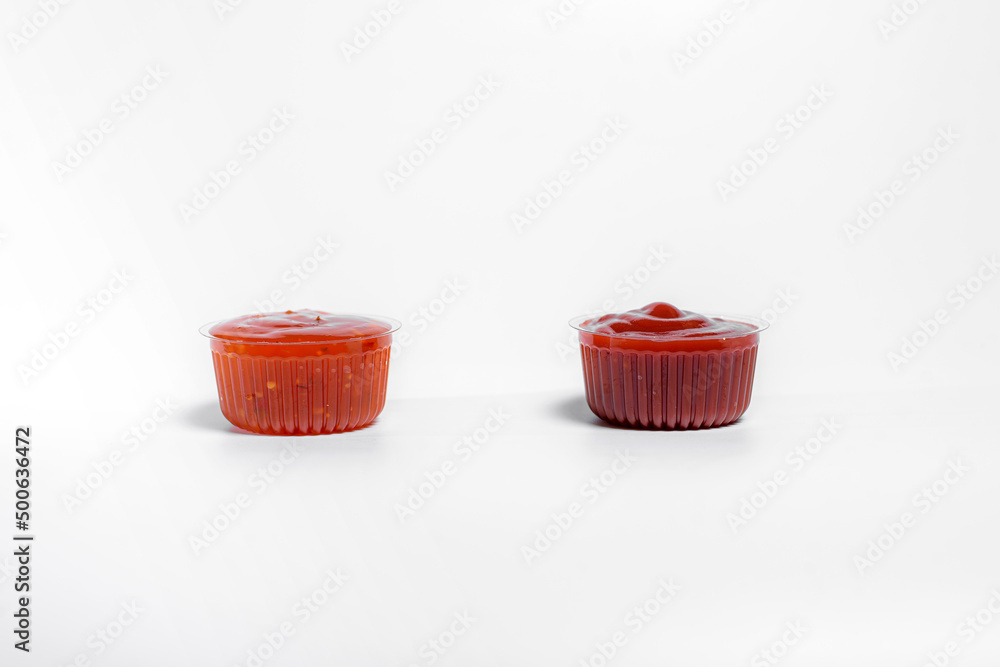 Ketchup and sauce in transparent boxes stands on a white background Ketchup and sauce in transparent boxes stands on a white background
