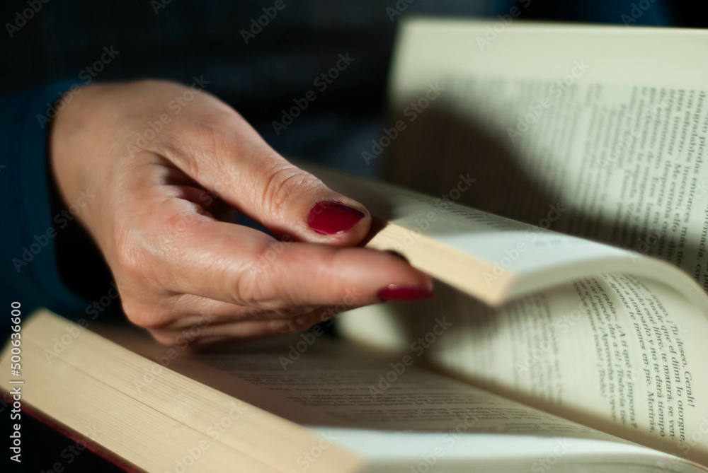 Hands holding a book that an elderly woman is reading using her fingers on the lines filled with words Hands holding a book that an elderly woman is reading using her fingers on the lines filled with words