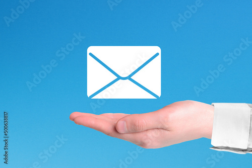 Hand holding email icon on blue background. Email marketing and newsletter