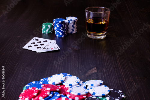 Poker game with pot of chips cards and a drink