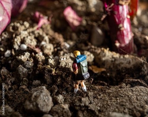 Small miniature person hiking on dirt landscape outdoors
