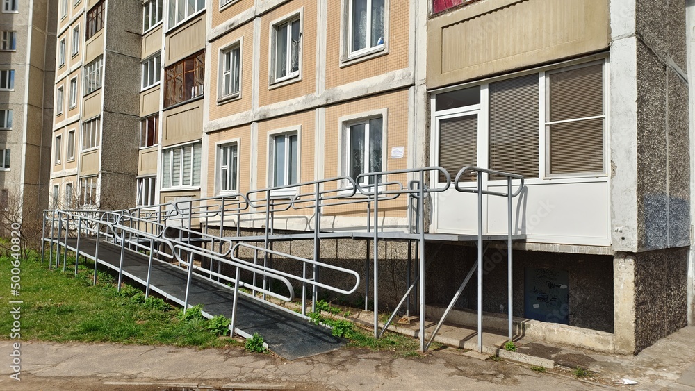 A ramp with metal railings is installed to enter a residential building for people with disabilities in wheelchairs. This creates a barrier-free environment