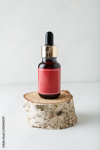 Face skin care cosmetics. Brown bottle of azelaic or hyalurone acid on wooden cross section cut on white background. Mockup, verticasl shot photo