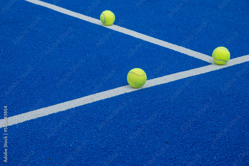 racket sports, three balls on the lines of a blue paddle tennis court