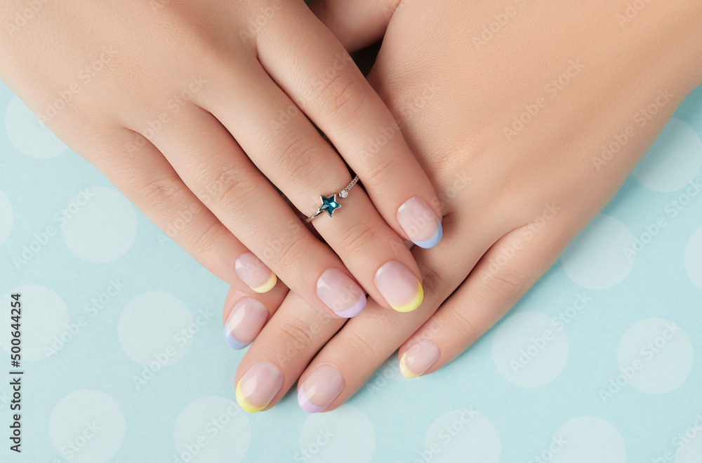 Beautiful womans hands with spring summer nail design on blue background